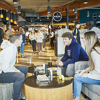 three students sitting in miller dining commons talking