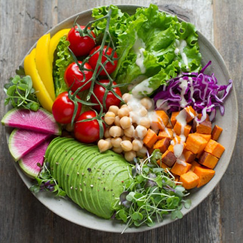 plate of food with sliced avocado, cherry tomatoes, lettuce, chickpeas, and cabbage