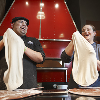 two staff members making pizza dough