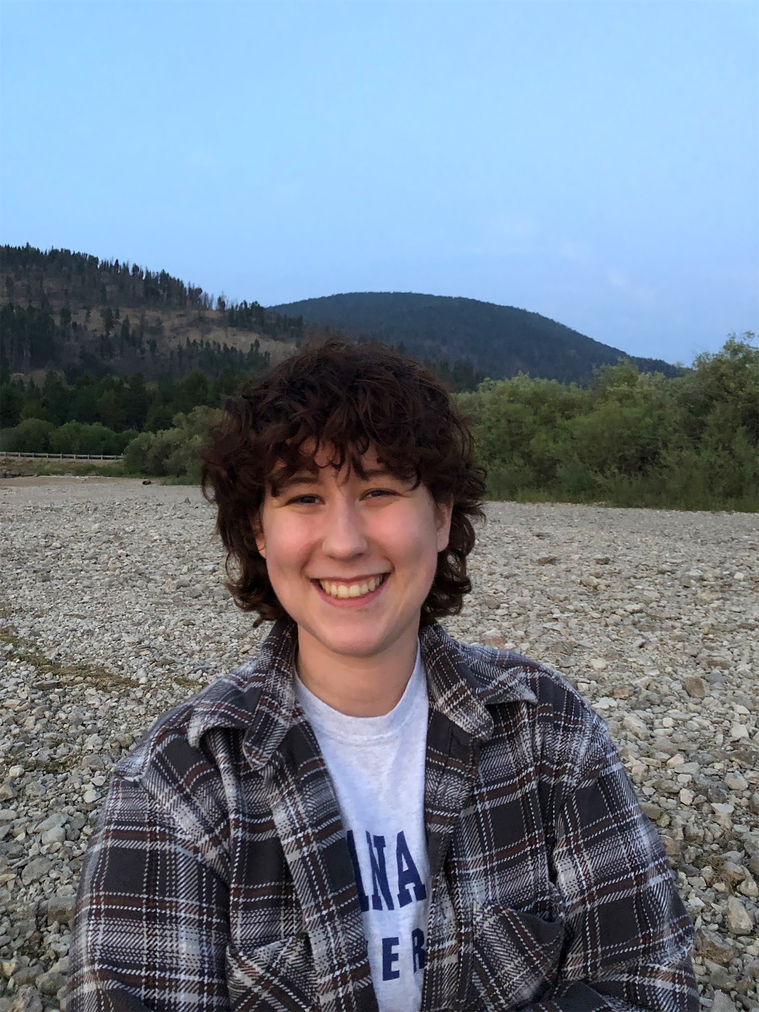 Dark haired woman smiling with a wilderness background