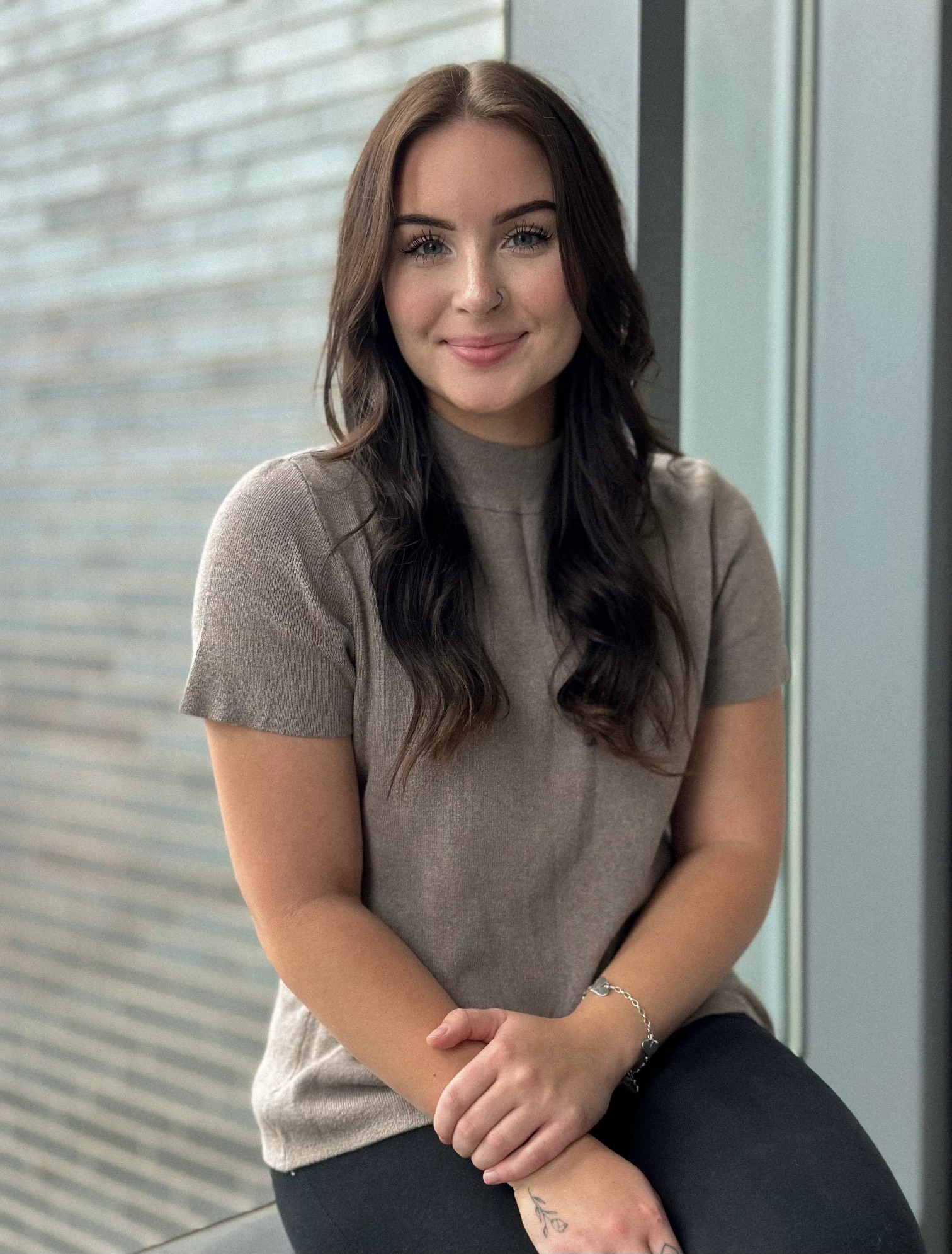 Dark haired young woman sitting on a window sill