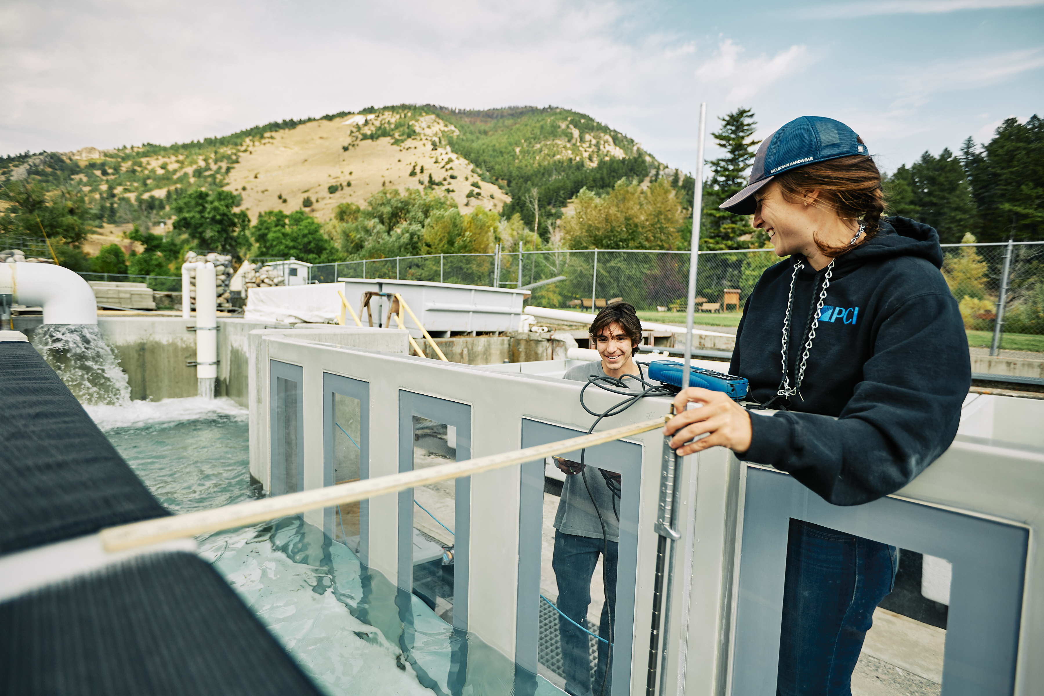 Megan and Anthony, students at Montana State University, take measurements at the outdoor flume at the Bozeman Fish Technology Center