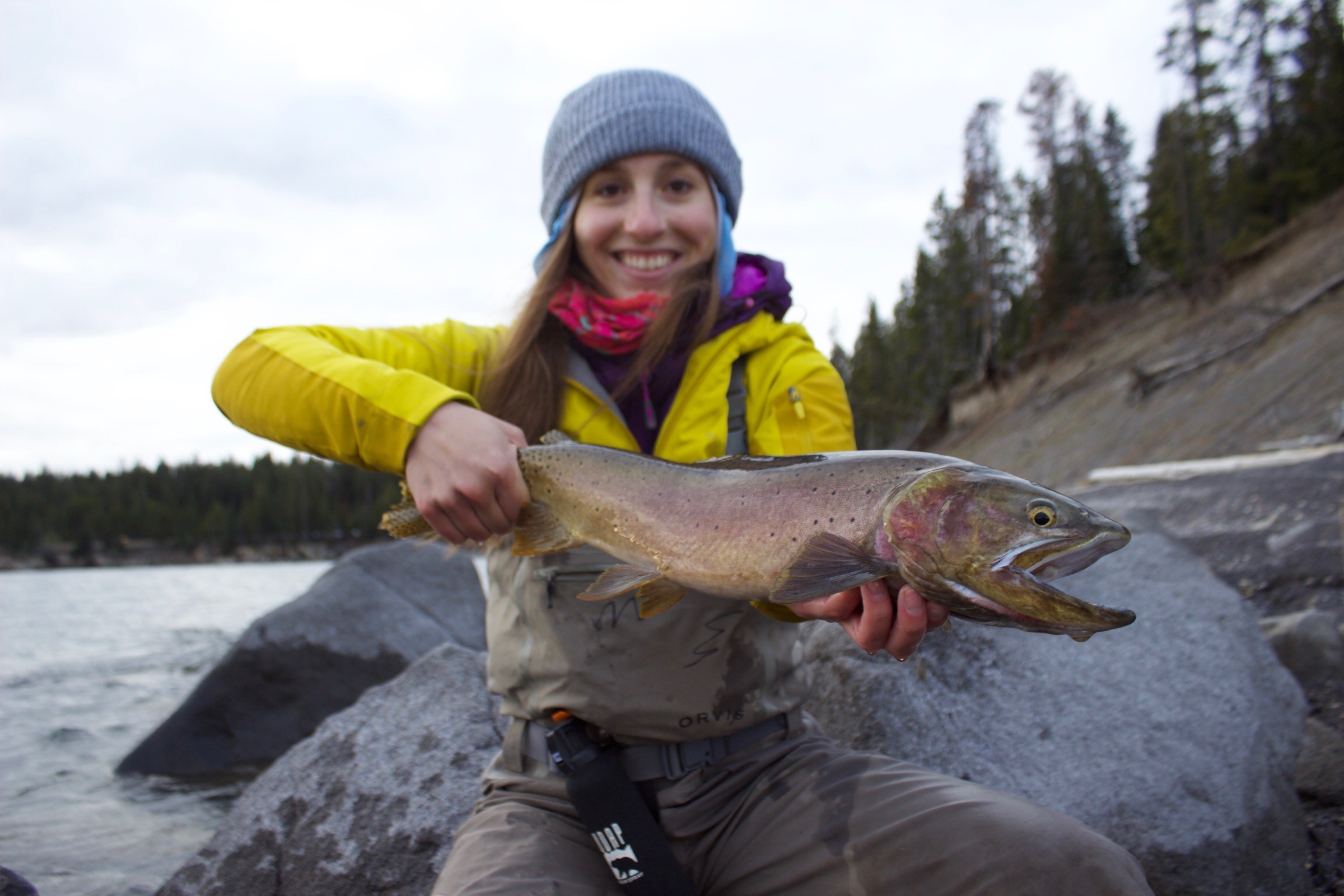 Hayley holding a trout over a river