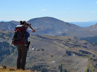 Student glassing through binoculars from above mountains