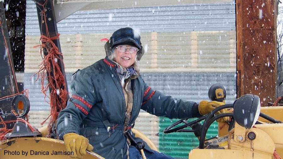 female driving tractor in winter with snow falling