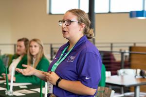 girl in purple shirt talking to a group of youth