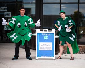 boy and gril dressed as 4-H clover with welcome sign