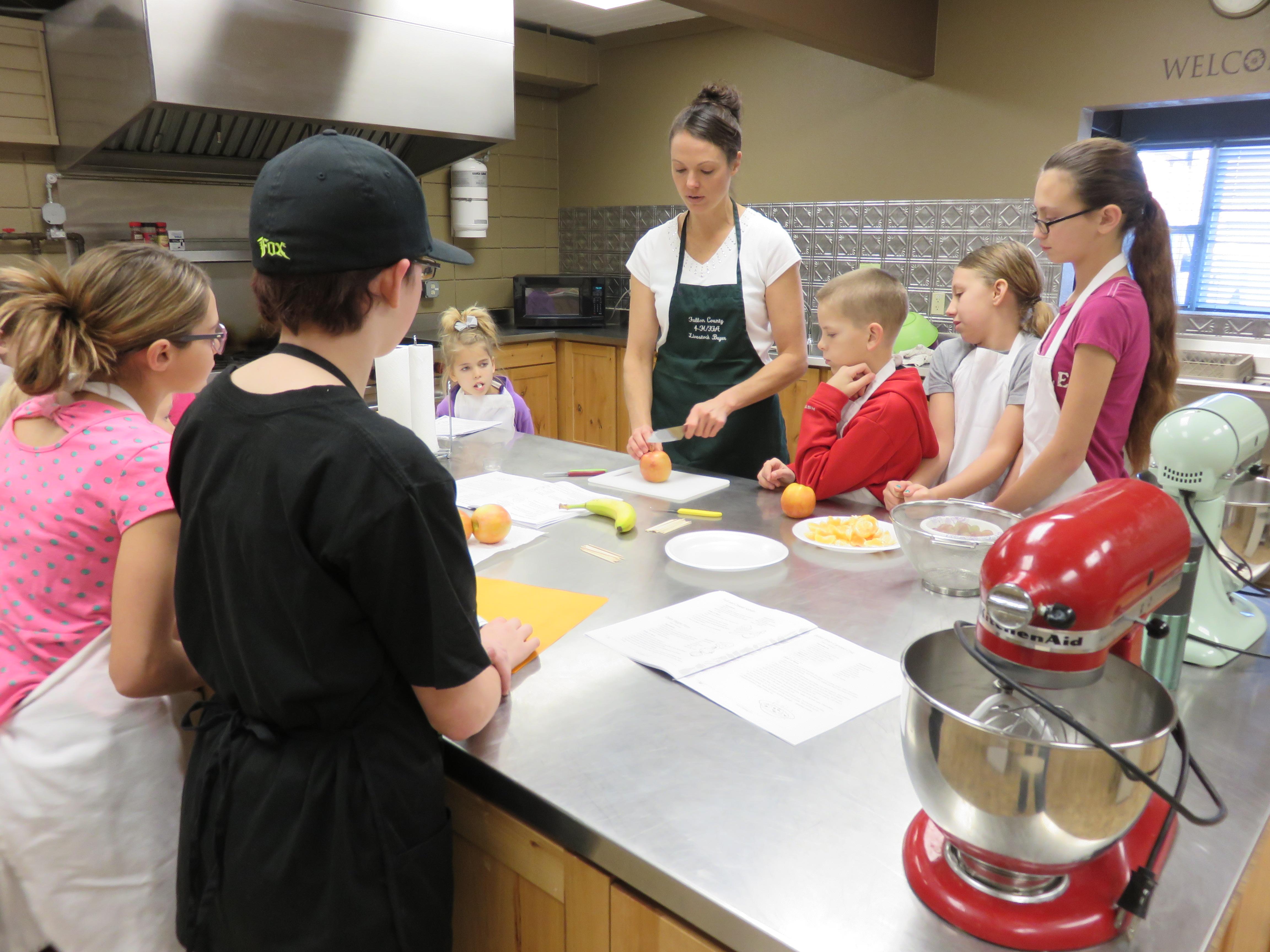 A female volunteer leads youth in a cooking project.