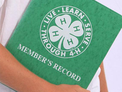 child holding green 4-H record book folder