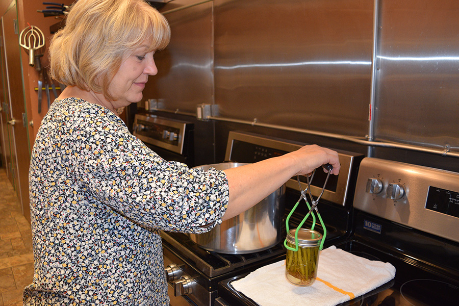 MSU Alum, Karla Breding removes a jar from the canning kettle during class.