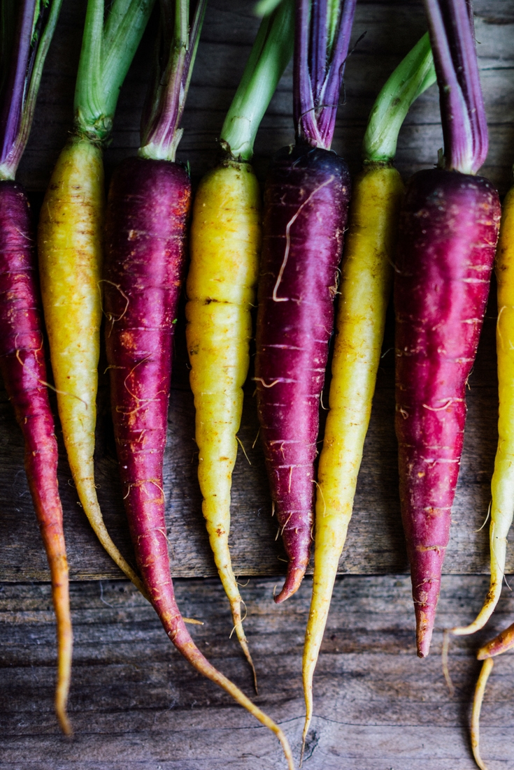 A row of purple and yellow carrots.