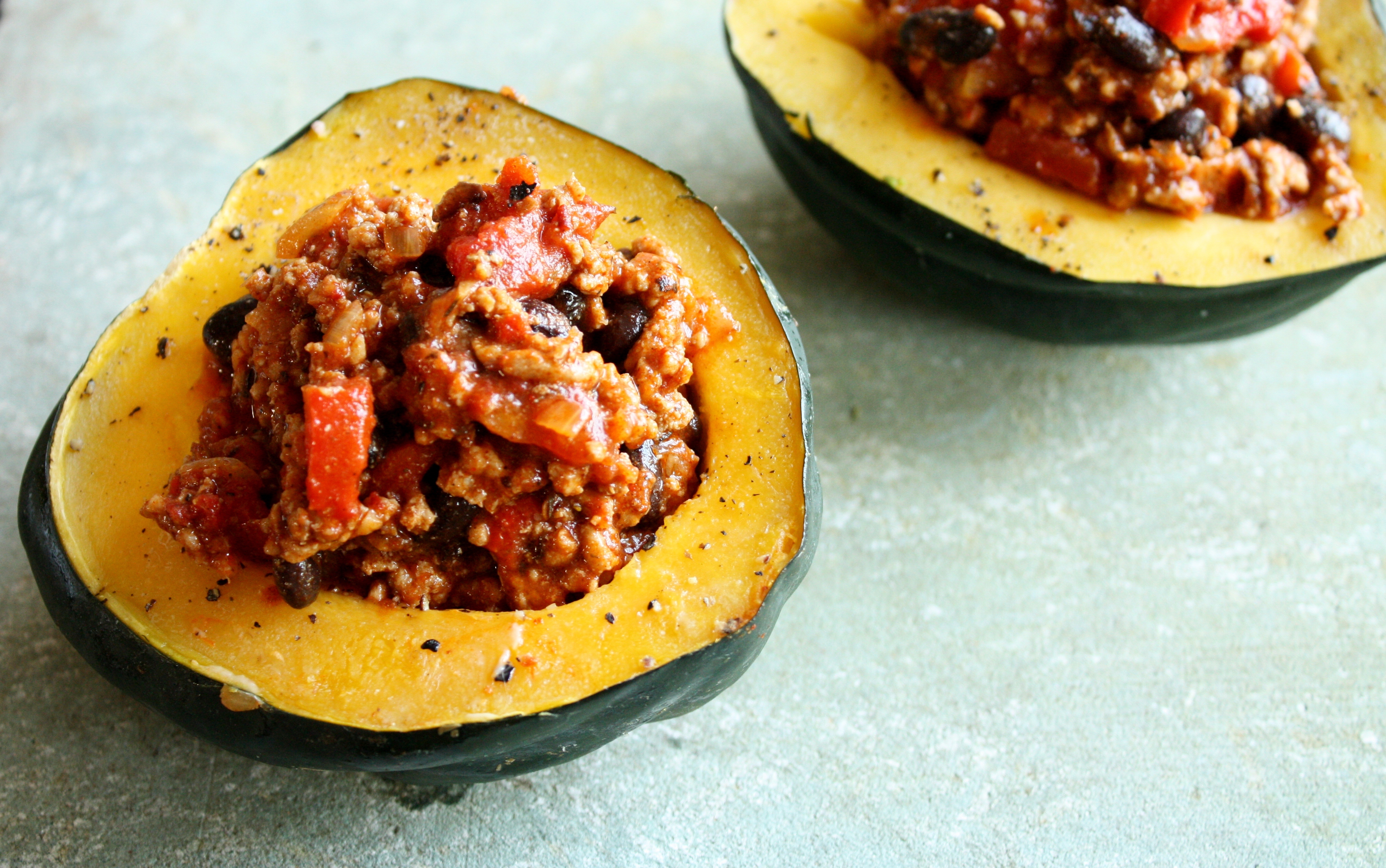 A yellow acorn squash cut in half and filled with meat and pasta sauce.