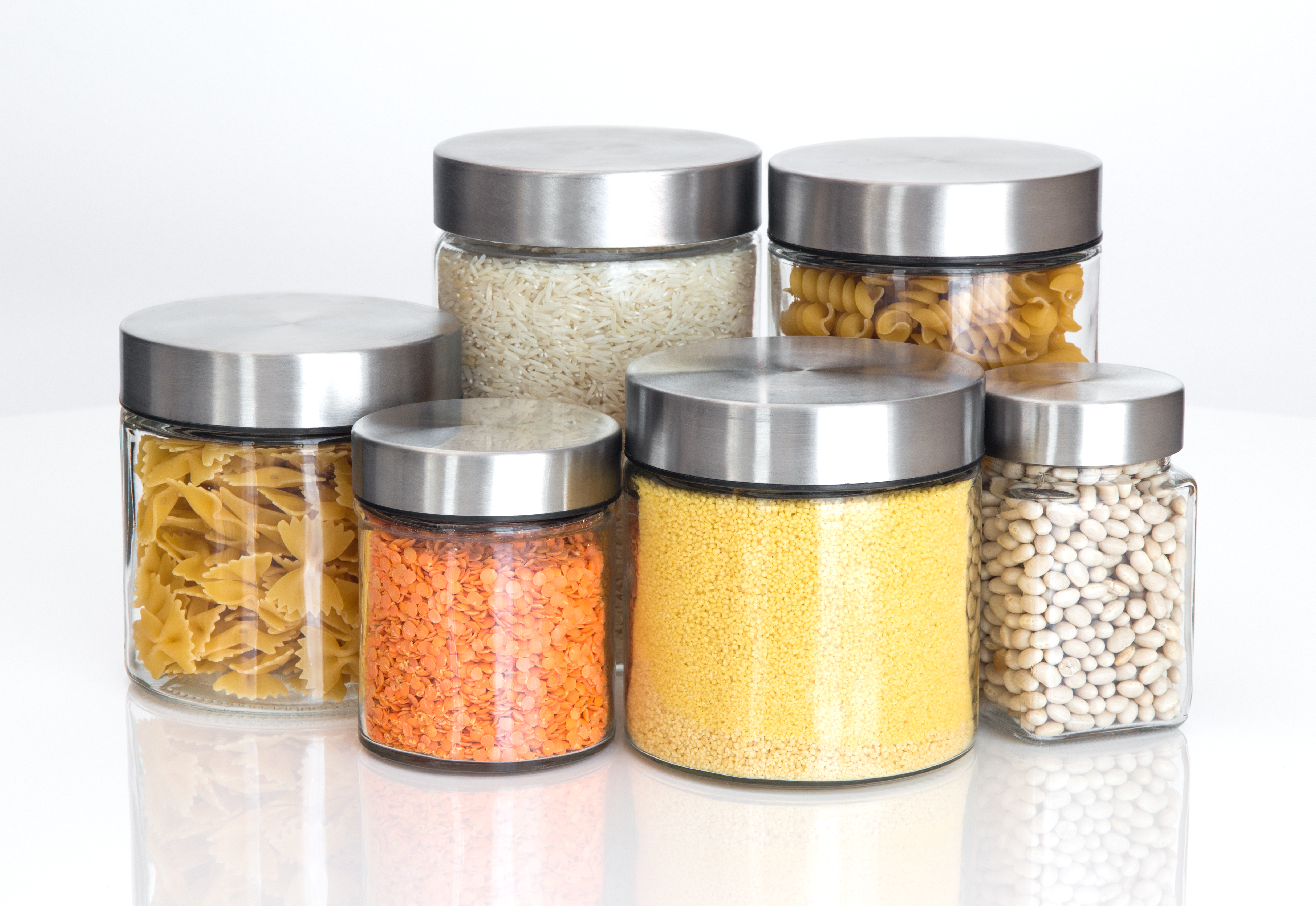 Six jars containing various dry goods such as lentils, beans, and pasta.
