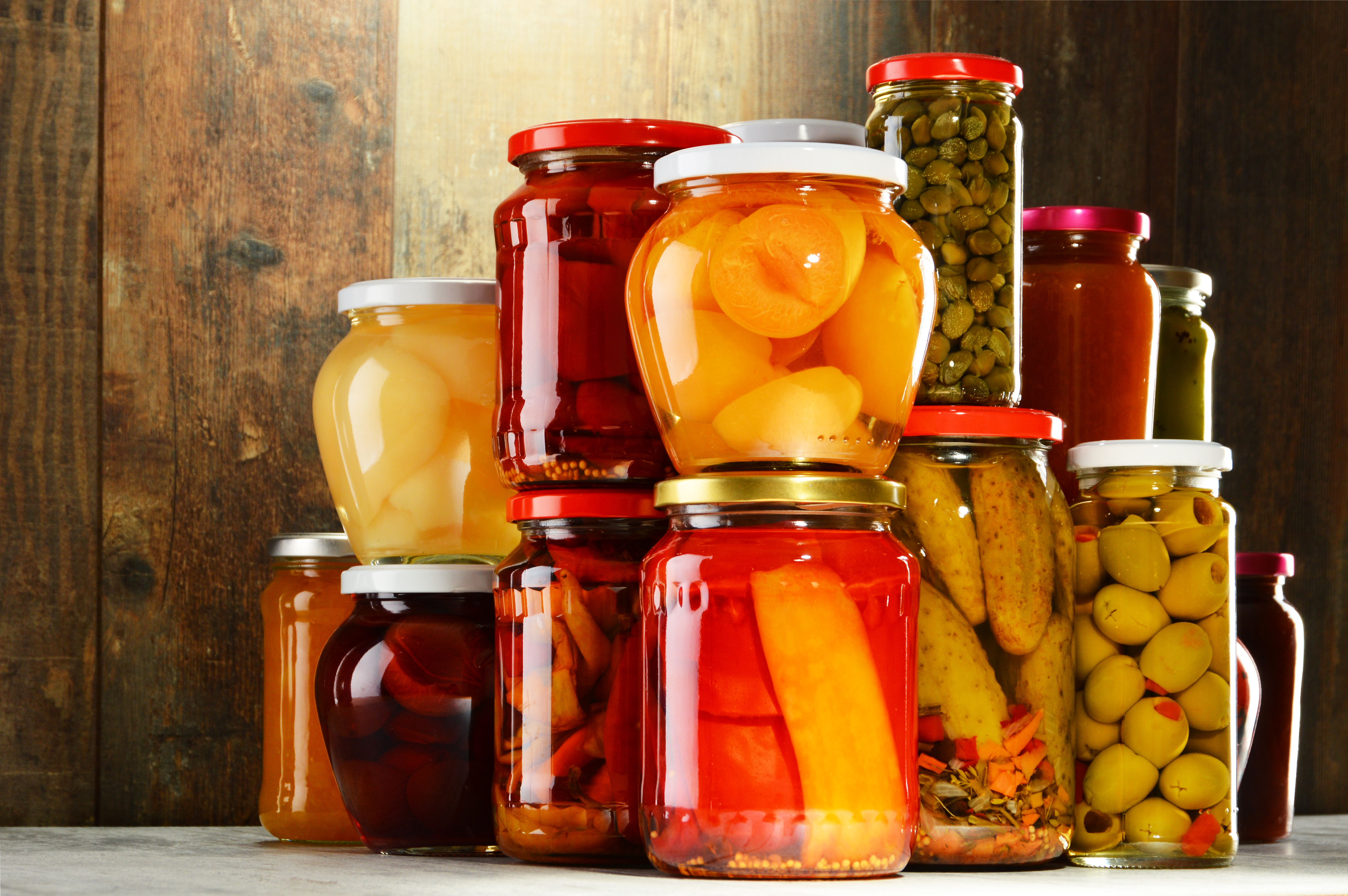 Various sizes and shapes of jars stacked on top of eachother, filled with fruits and vegetables.