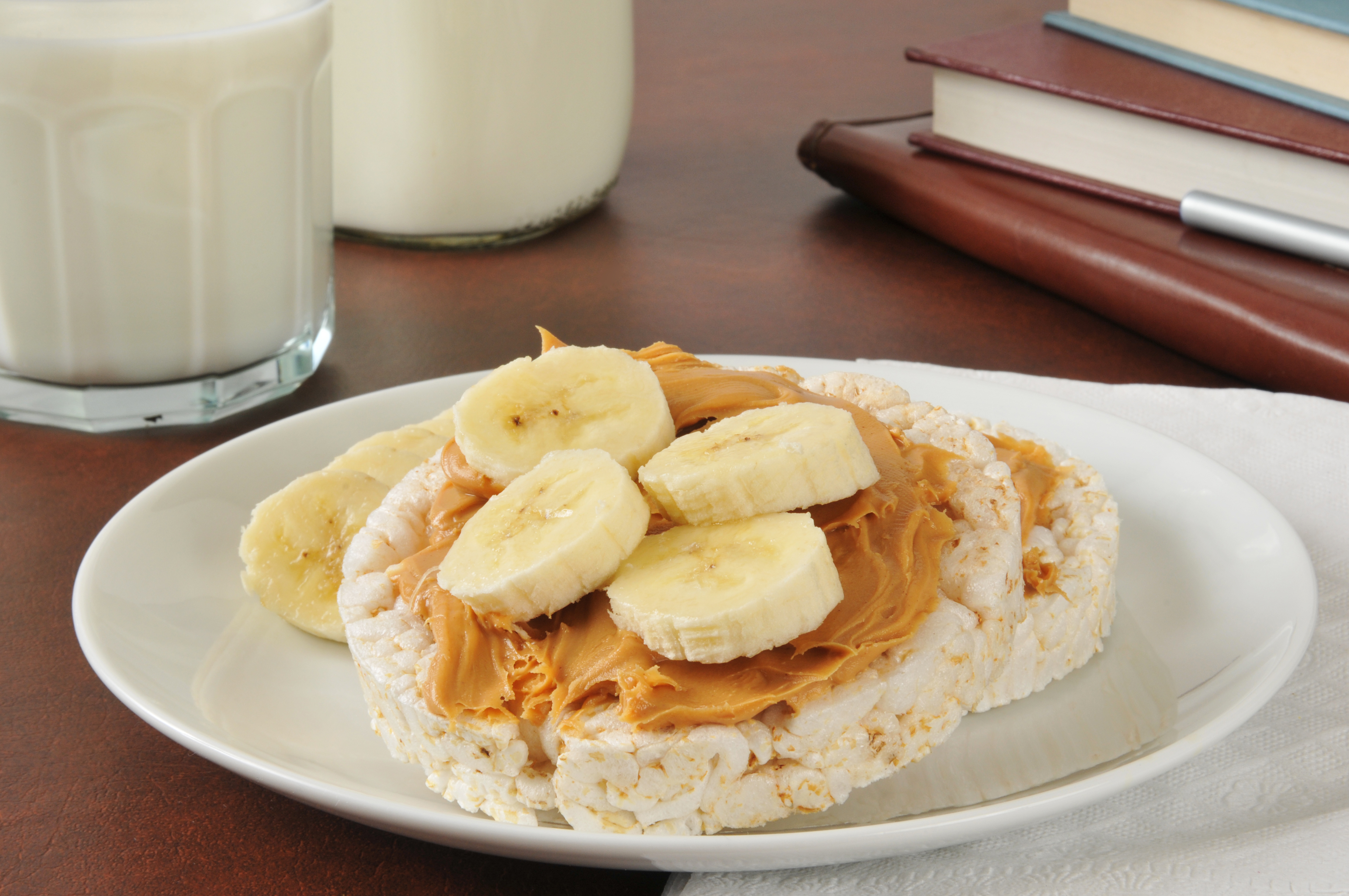 A plate with a rice cake topped with peanut butter and four banana slices.