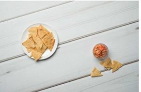 Baked tortilla chips on a plate next to a small bowl of salsa.