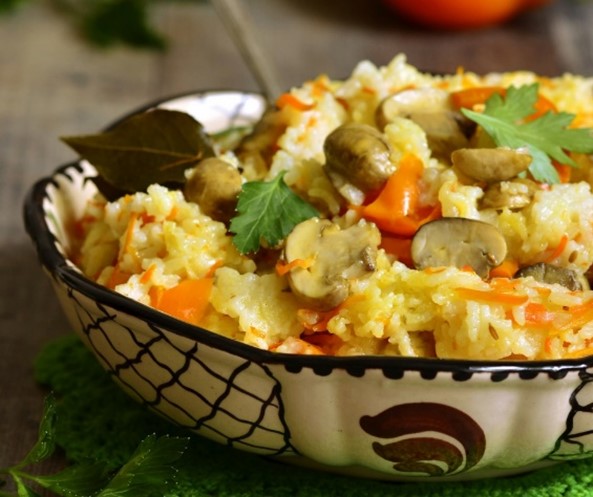 A bowl of barley pilaf containing mushrooms and bell peppers.