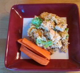 A plate of chicken/turkey, broccoli, and rice casserole with a side of carrot sticks. 