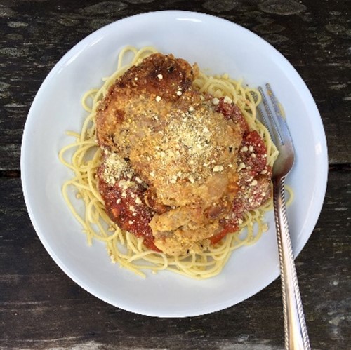A plate of chicken parmesadn over pasta noodles.