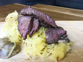 A serving of spaghetti squash and mushrooms topped with strips of elk steak.