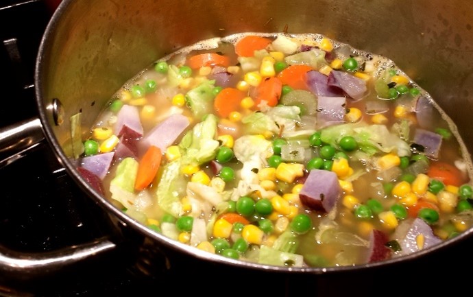 An image of Mrs. Pommer's Vegetable Soup in a large pot on a stovetop made with purple potatoes.
