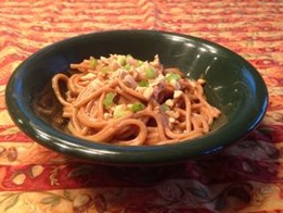 An image of noodles in creamy peanut sauce in a green bowl.