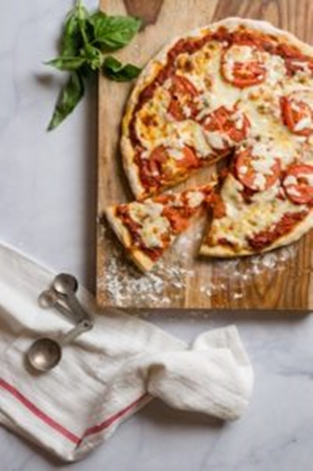 An image of quick and easy pizza on a wooden cutting board.