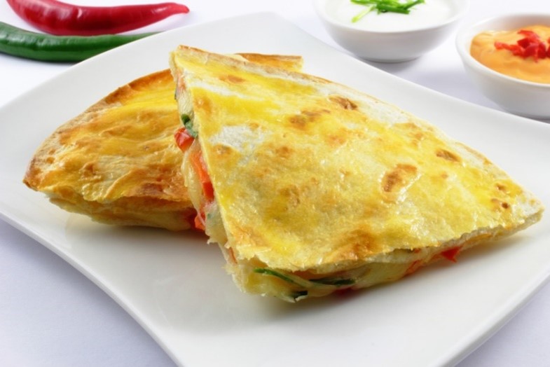 An image of a spinach and pepper quesadilla on a white plate.