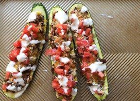 An image of three sliced zucchinis filled with ground beef and tomatoes.