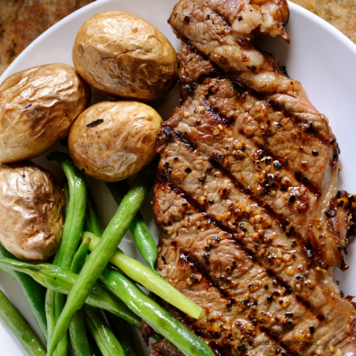 Image of a grilled sirloin steak, pared with roasted potatoes and green beans.