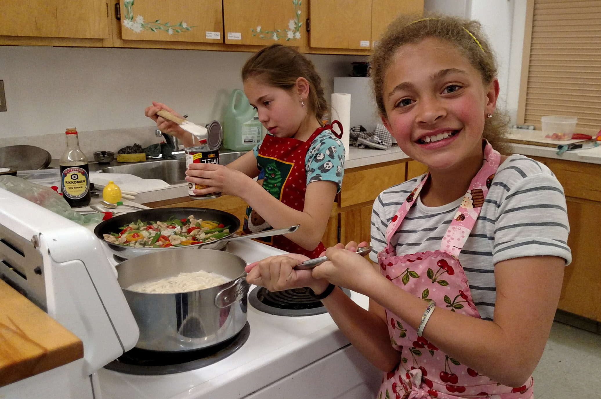 Two kids are cooking in a kitchen