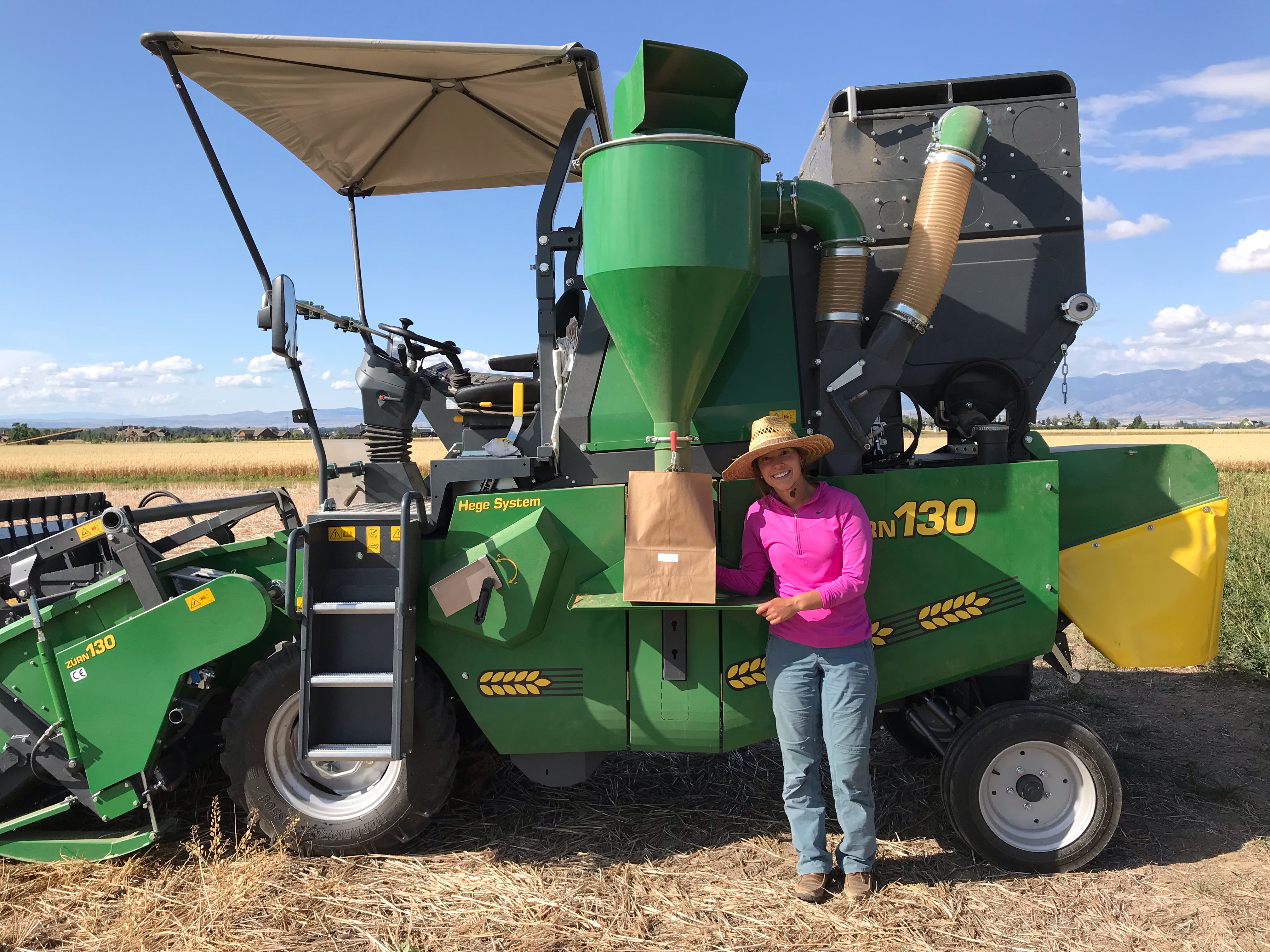 graduate student standing next to grain combine