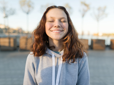 A teenager smiles serenely with her eyes closed