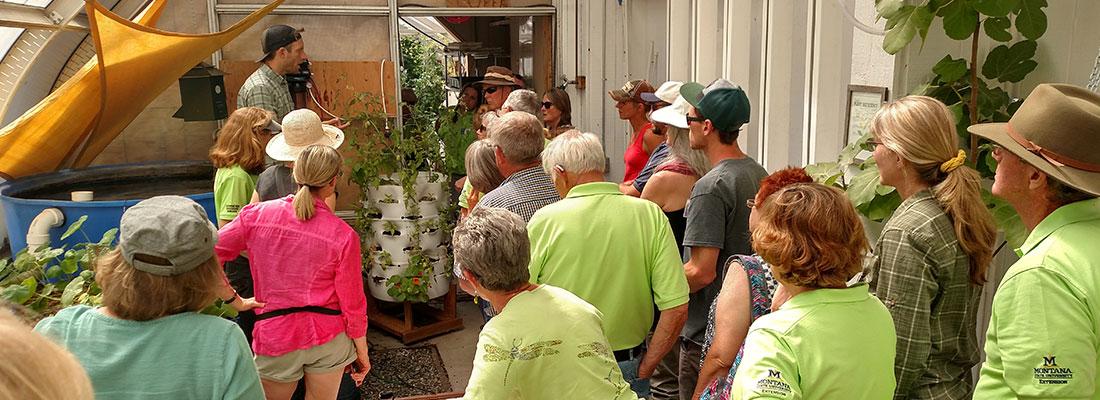 Group of people listening to speaker in a greenhouse setting