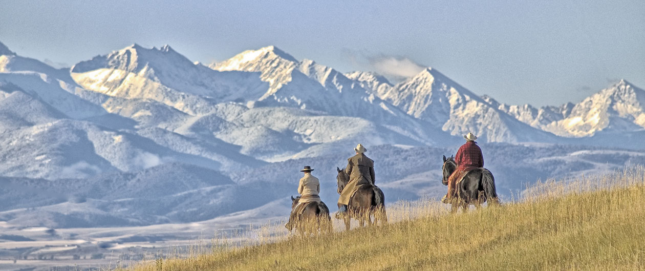 montana mountain range with cowboys on horses