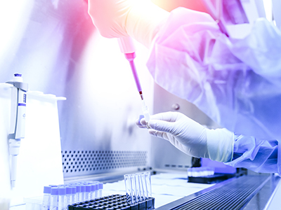 someone pipetting a liquid into test tubes in lab