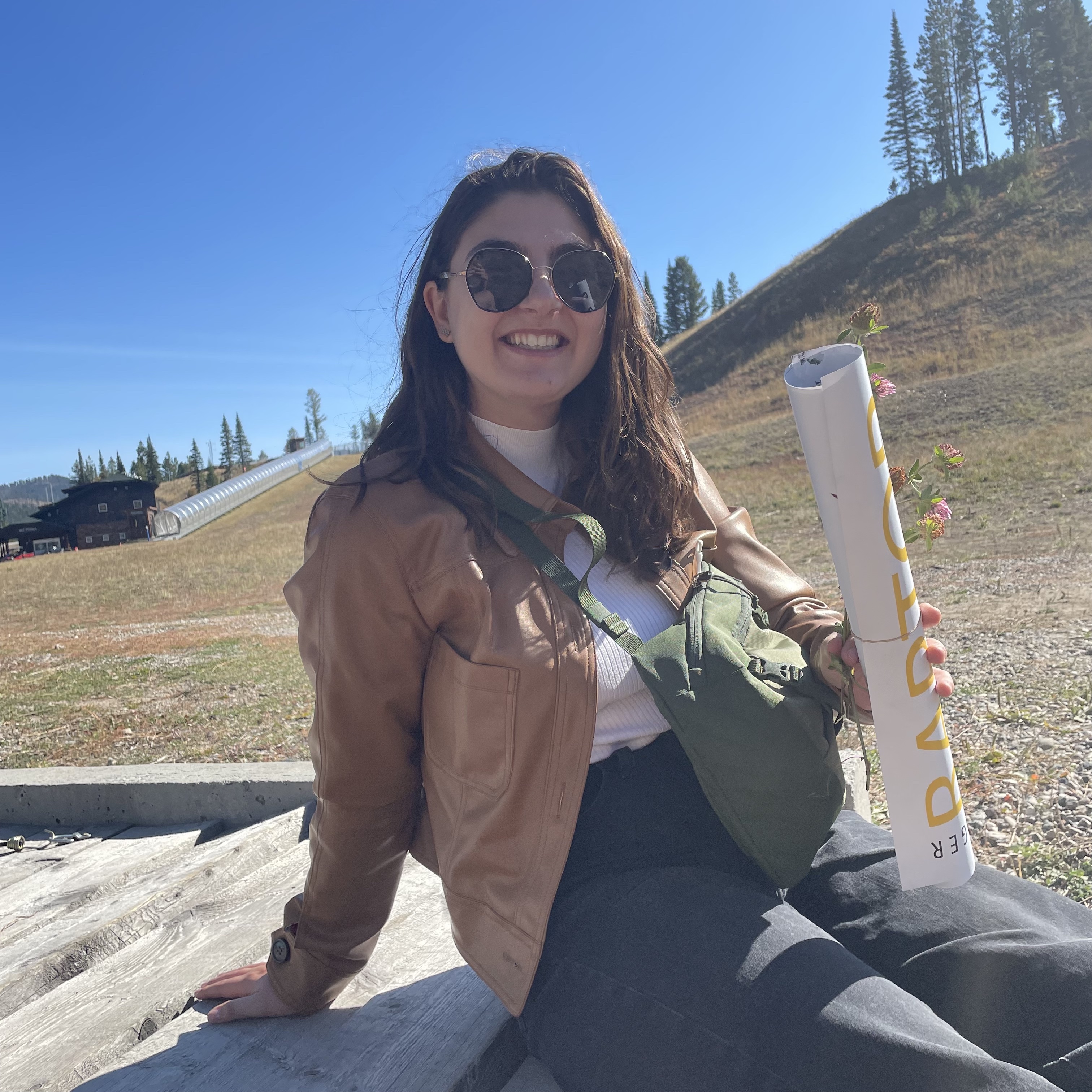 Melissa Widas, holding some sort of paper roll, at Bridger, in the summer!