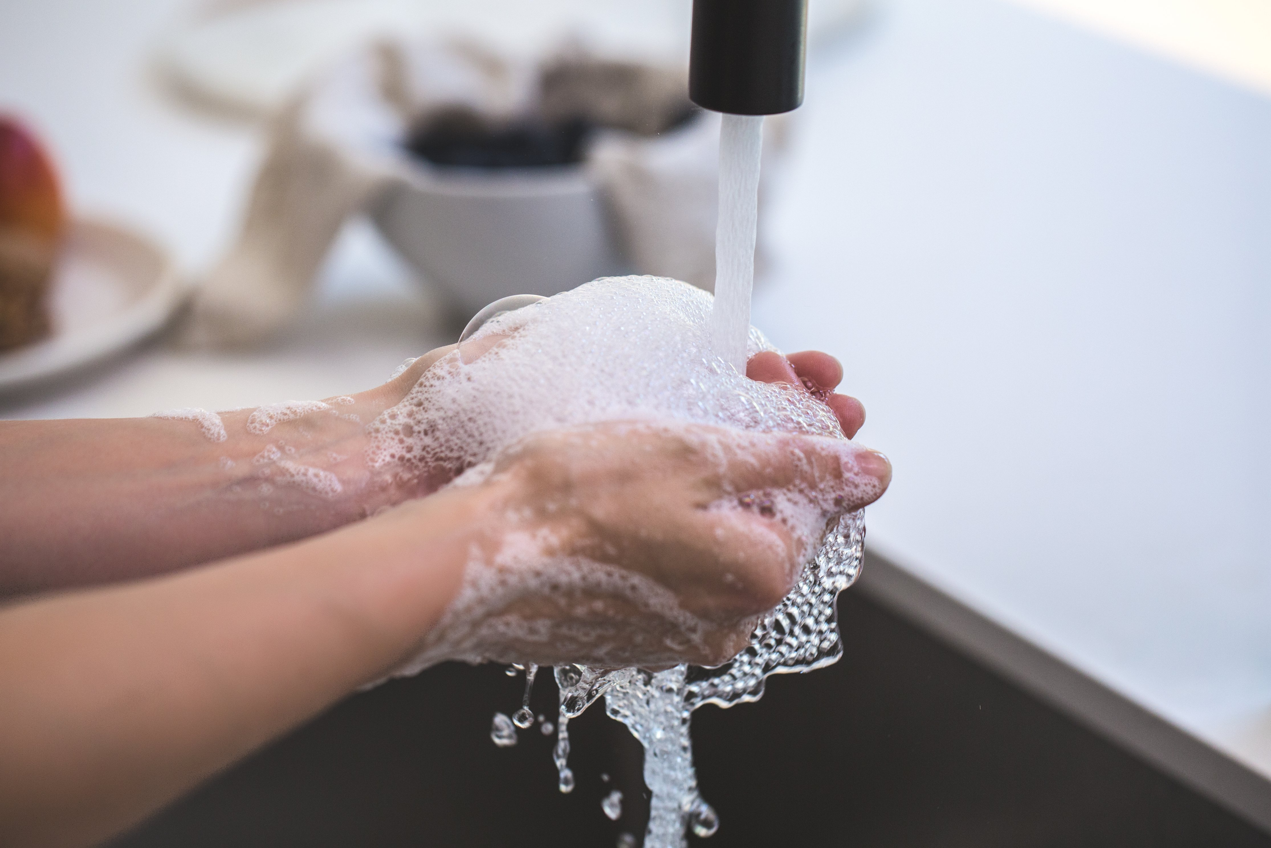 Washing hands with soap lather under facet tap