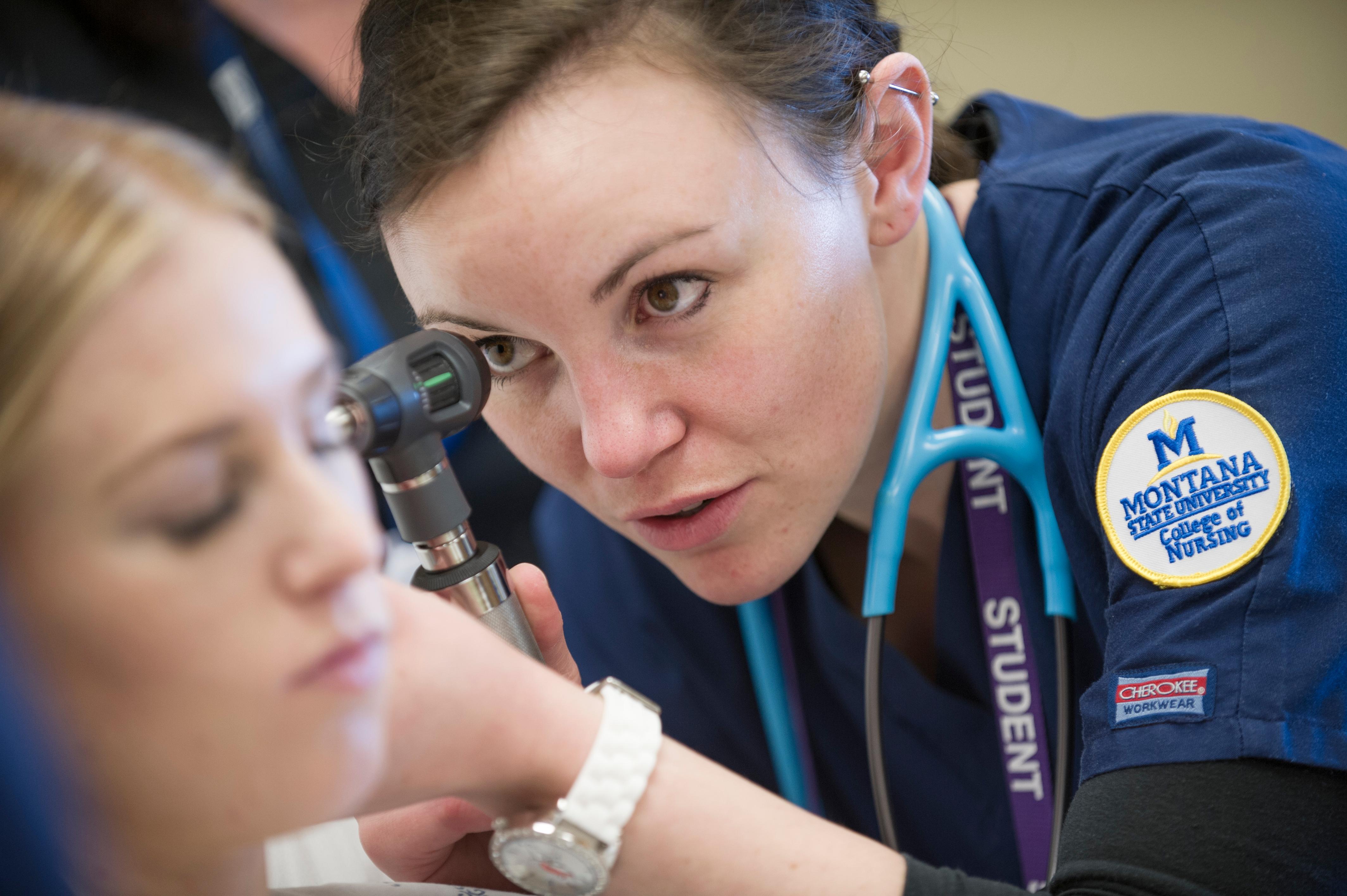 Female nursing student checking another student's ears