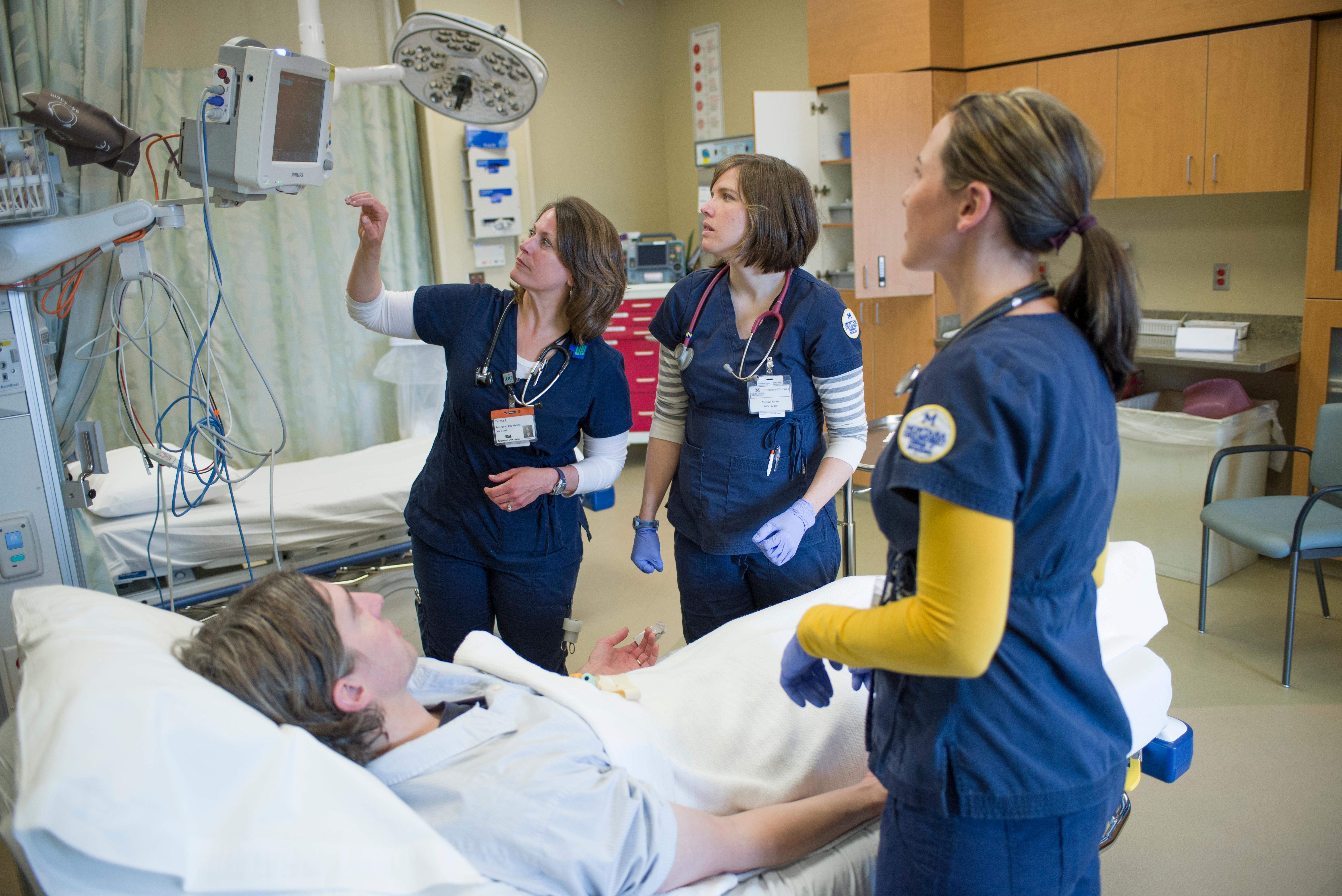 Three nursing students using training labs to monitor another student