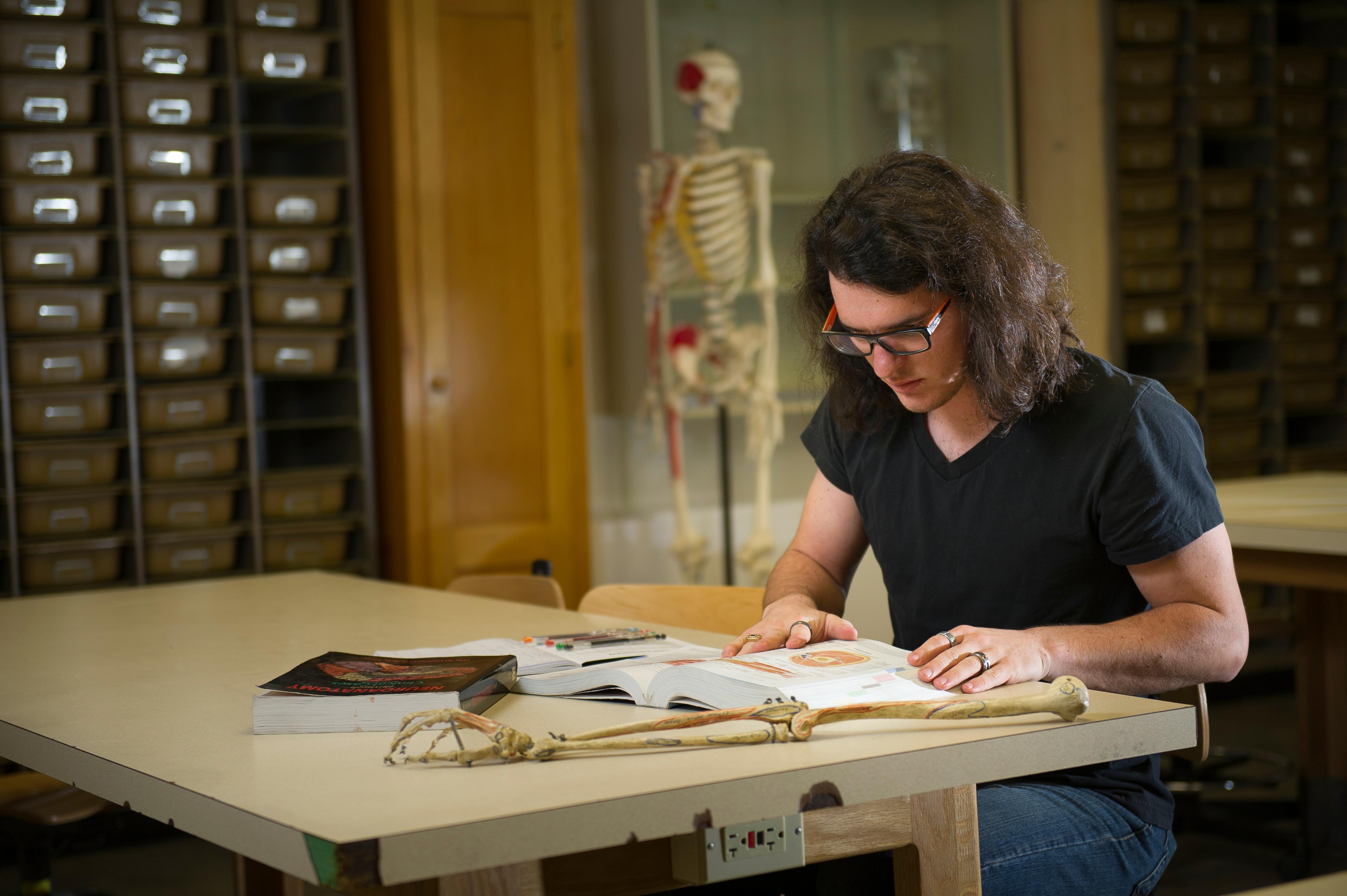 Male student studying next to a skeleton