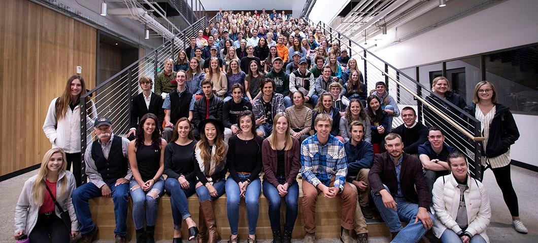 The class of honors students sitting on the stairs in a large class building.