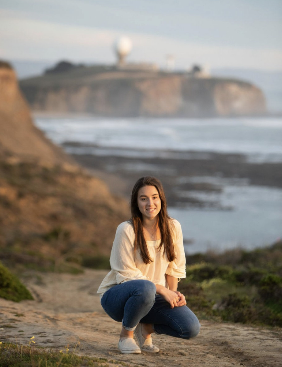 a girl in front of a cliff and a lake