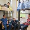 Students hanging out on top of a loft and in desk chairs in a double room.