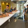 Students sitting at and hanging out around the kitchen and the island in the lobby.