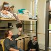 Students hanging out on top of a loft and in desk chairs in a double room.