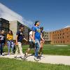 Students walking on sidewalk next to the building and the building in the background.