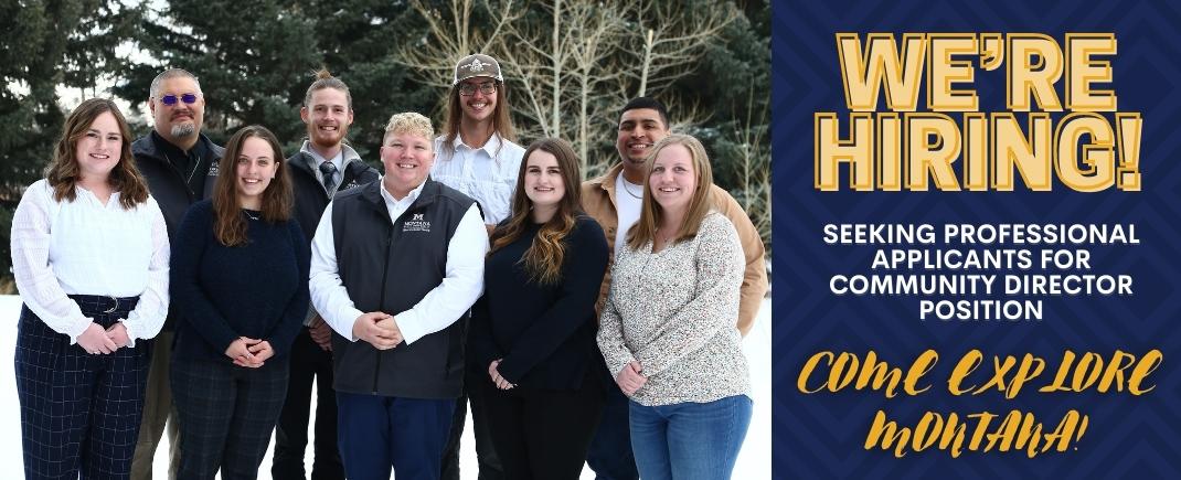 Picture of 10 community directors outside of hyalite hall with right side banner that states 'We're Hiring! Seeking Professional Applicants For Community Director Position. Come Explore Montana!"