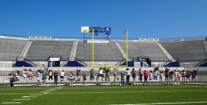 A group of students are photgraphed mid-air while jumping simultaneously in the bobcat stadium.