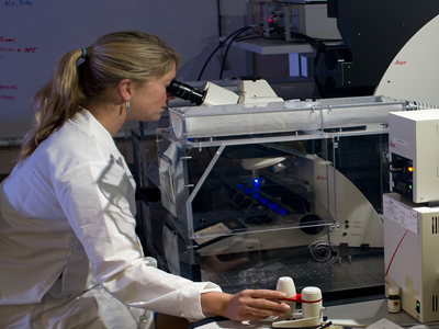 A researcher looking at a microscope.